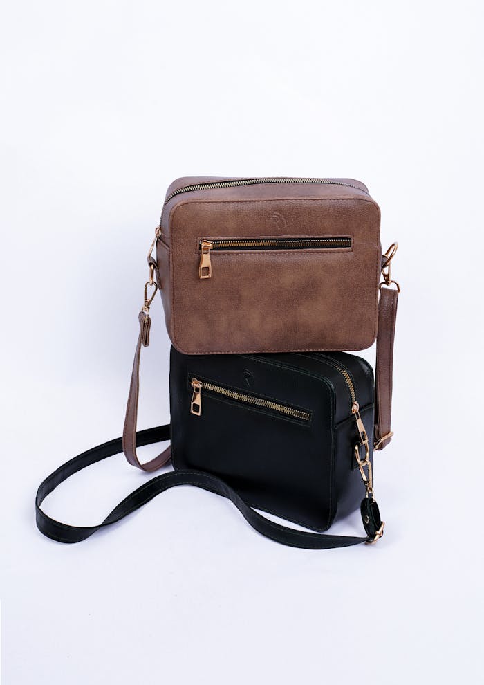 Minimalist studio shoot of brown and black leather bags on a white background.