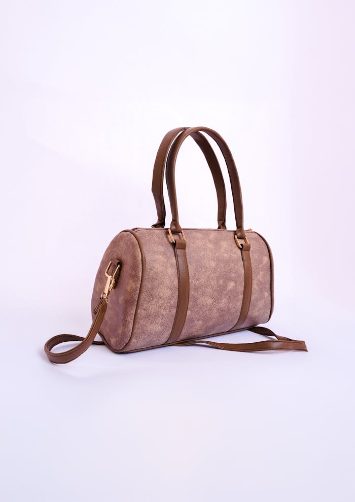 Stylish brown leather handbag with dual handles and long strap, perfect for fashion-forward individuals.